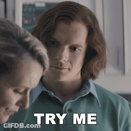 A Man In A Green Shirt Is Standing Next To A Woman With The Words Try Me Below Him GIF