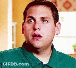 A Man In A Green Shirt Looks Surprised And Shocked GIF