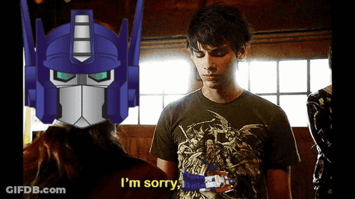 A Man In A Green Shirt Says I 'M Sorry In Front Of A Robot Head GIF