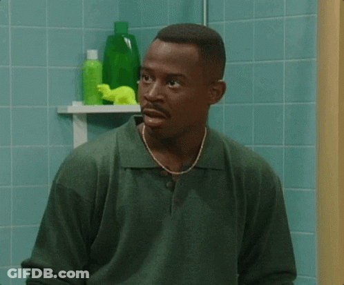 A Man In A Green Shirt Stands In Front Of A Bathroom Shelf With Green Bottles On It GIF