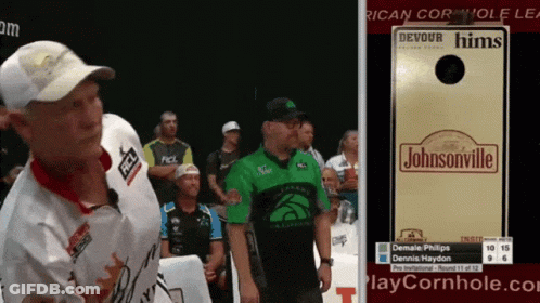 A Man In A Green Shirt Stands Next To A Sign That Says Johnsonville GIF
