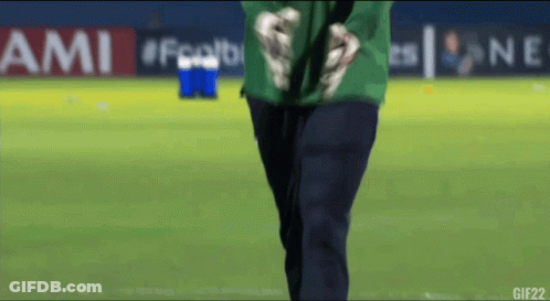 A Man In A Green Shirt Stands On A Soccer Field In Front Of An Ami Banner GIF