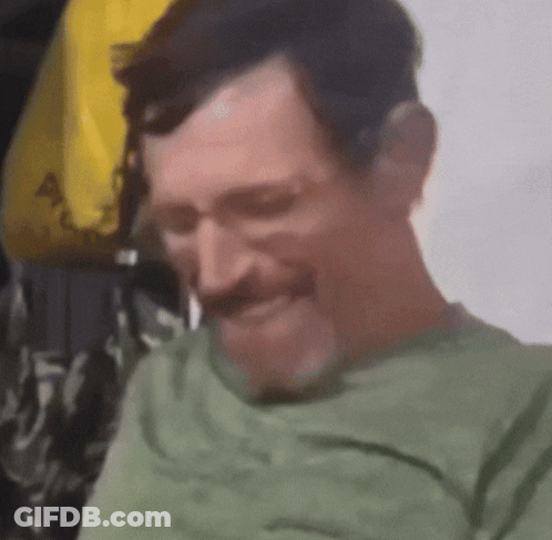 A Man In A Green Shirt With A Mustache Is Smiling GIF