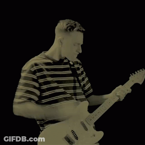 A Man In A Green Striped Shirt Is Playing A Guitar GIF