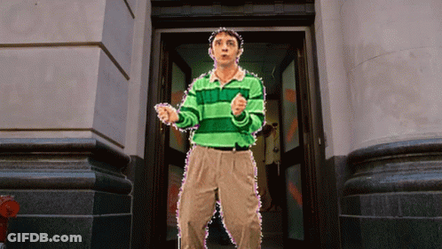 A Man In A Green Striped Shirt Is Standing In Front Of A Building GIF