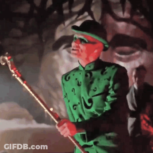 A Man In A Green Suit And Hat Is Holding A Gold Cane GIF