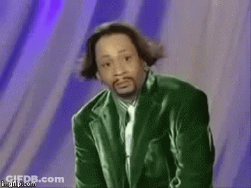 A Man In A Green Suit And Tie Is Standing In Front Of A Purple Wall . GIF