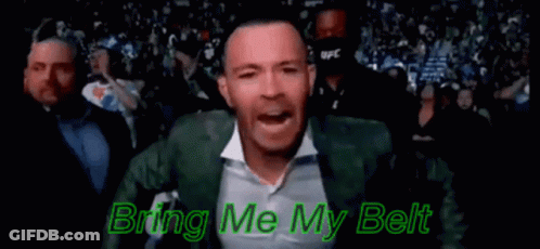 A Man In A Green Suit And White Shirt Is Standing In Front Of A Crowd And Singing . GIF