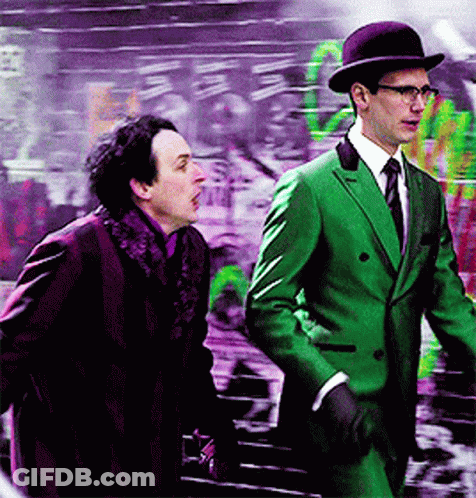 A Man In A Green Suit Stands Next To Another Man GIF