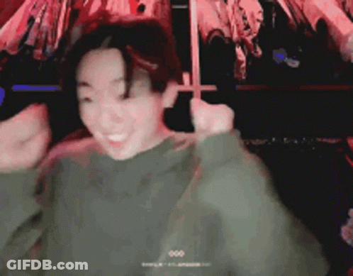A Man In A Green Sweater Is Making A Funny Face While Dancing . GIF