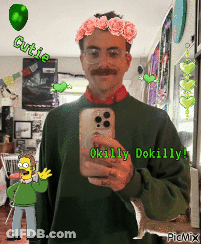 A Man In A Green Sweater Is Taking A Picture Of Himself With A Flower Crown On His Head GIF