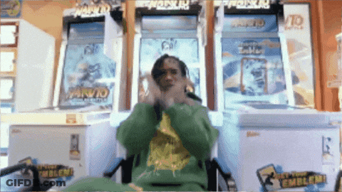 A Man In A Green Sweatshirt Is Sitting In Front Of A Naruto Game GIF