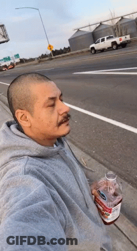 A Man In A Grey Hoodie Is Holding A Bottle Of Apple Cider Vinegar .. GIF