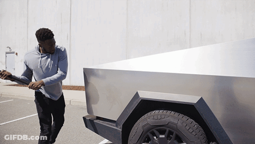 A Man In A Grey Hoodie Is Pushing A Silver Truck GIF