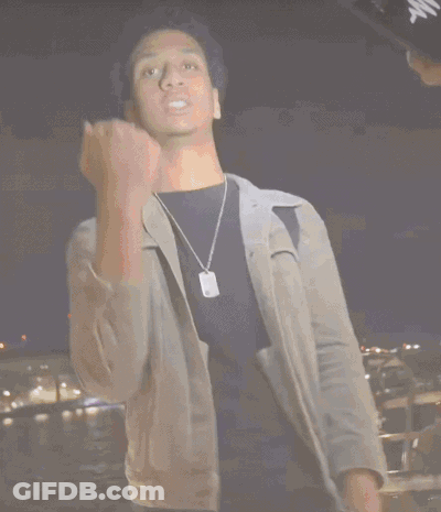 A Man In A Grey Jacket Is Holding A Stack Of Money In His Hand GIF
