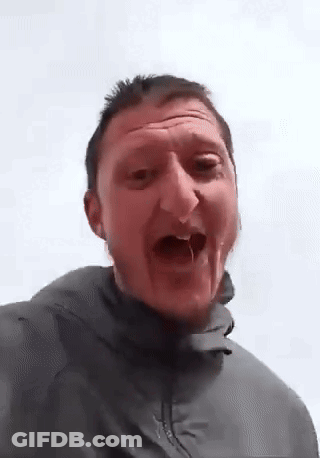 A Man In A Grey Jacket Is Making A Funny Face . GIF