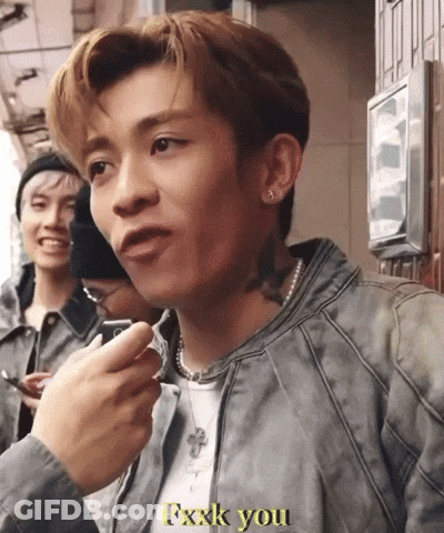 A Man In A Grey Jacket Says Fxxxk You In Yellow Letters GIF