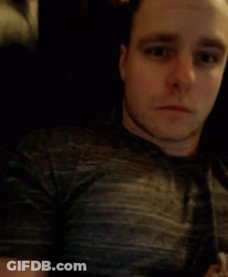 A Man In A Grey Shirt Is Blowing His Nose With A Tissue GIF