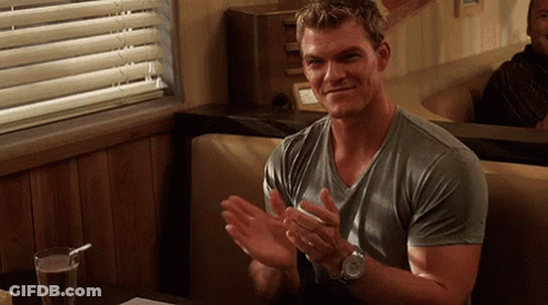 A Man In A Grey Shirt Is Clapping His Hands In A Diner . GIF