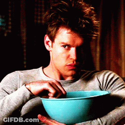 A Man In A Grey Shirt Is Holding A Blue Bowl Of Food GIF