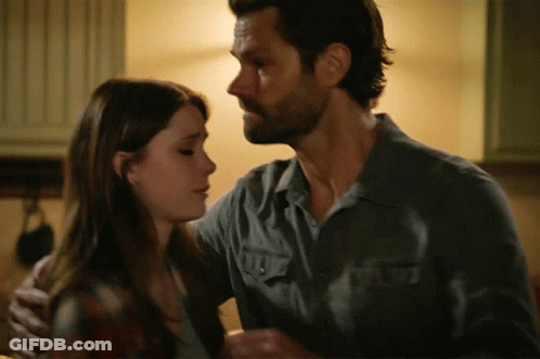 A Man In A Grey Shirt Is Hugging A Woman GIF