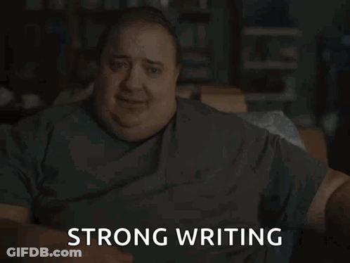 A Man In A Grey Shirt Is Sitting Down And Says Strong Writing GIF