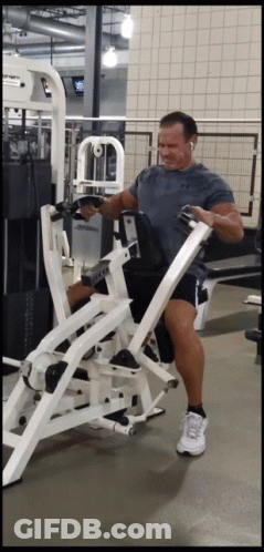 A Man In A Grey Shirt Is Using A Machine In A Gym That Has The Word Cybex On It GIF