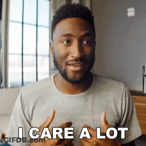 A Man In A Grey Shirt Says " I Care A Lot " In Front Of A Window GIF