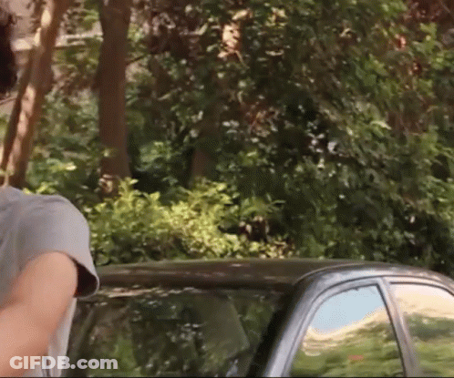 A Man In A Grey Shirt Stands Next To A Black Car GIF