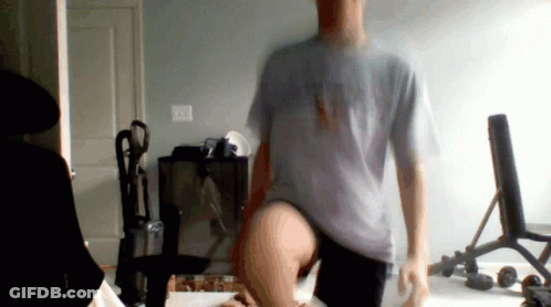 A Man In A Grey Shirt That Says Ny On It Is Standing In A Room GIF