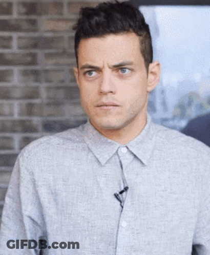 A Man In A Grey Shirt With A Microphone On His Collar GIF