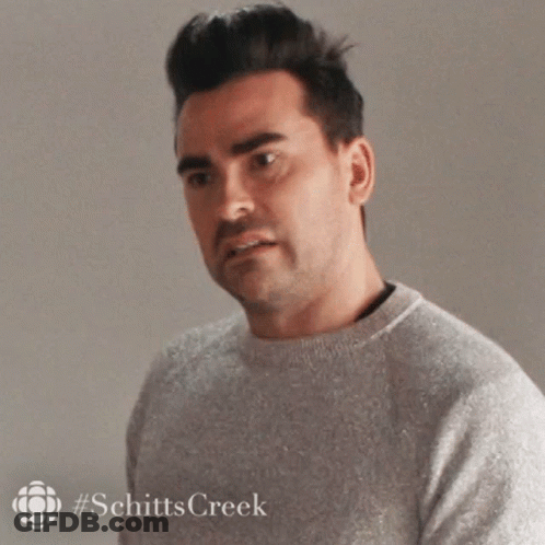 A Man In A Grey Sweater Is Looking At The Camera . GIF