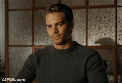 A Man In A Grey Sweater Is Smiling And Giving A Thumbs Up GIF
