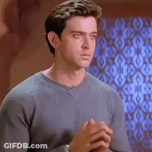 A Man In A Grey Sweater Looks At The Camera With His Eyes Closed GIF