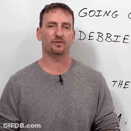 A Man In A Grey Sweater Stands In Front Of A White Board That Says Going Debbie The A GIF