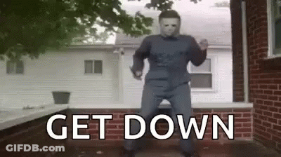 A Man In A Halloween Costume Is Dancing In Front Of A Brick House . GIF