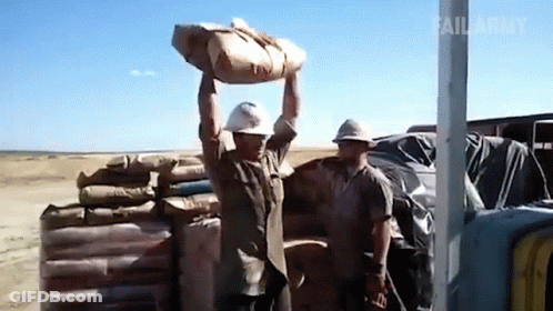 A Man In A Hard Hat Is Carrying A Bag Over His Head GIF