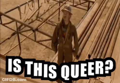 A Man In A Hard Hat Stands In Front Of A Wooden Structure With The Words Is This Queer Written Below Him GIF
