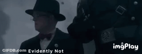 A Man In A Hat And Bow Tie Is Standing Next To A Man In A Black Uniform With The Words " Evidently Not " Above Him GIF