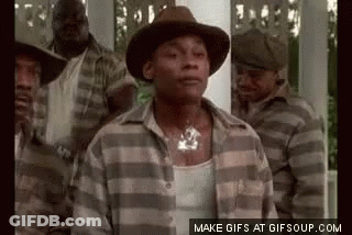 A Man In A Hat And Plaid Shirt Is Standing In Front Of A Group Of Men In Striped Shirts . GIF