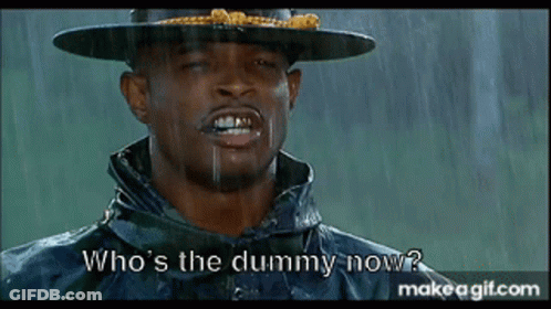 A Man In A Hat And Raincoat Is Asking Who 'S The Dummy Now . GIF