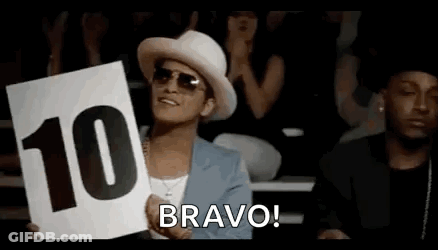 A Man In A Hat And Sunglasses Is Holding A Sign That Says `` Bravo '' . GIF