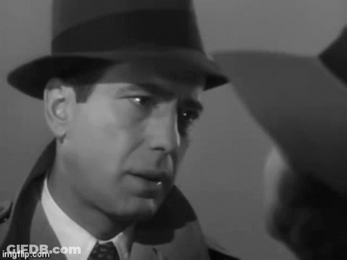 A Man In A Hat And Tie Is Looking At Another Man In A Suit . GIF