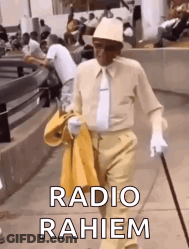 A Man In A Hat And Tie Is Walking Down The Street With A Cane And A Yellow Jacket . GIF