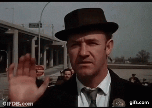 A Man In A Hat And Tie Is Waving His Hand In Front Of A Group Of People . GIF