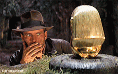 A Man In A Hat Is Covering His Mouth While Looking At A Gold Object GIF