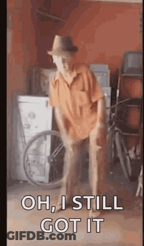A Man In A Hat Is Dancing In A Garage With A Wheelchair . GIF