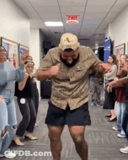 A Man In A Hat Is Dancing In A Hallway With A Group Of People . GIF