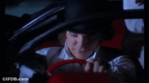 A Man In A Hat Is Driving A Red Car GIF