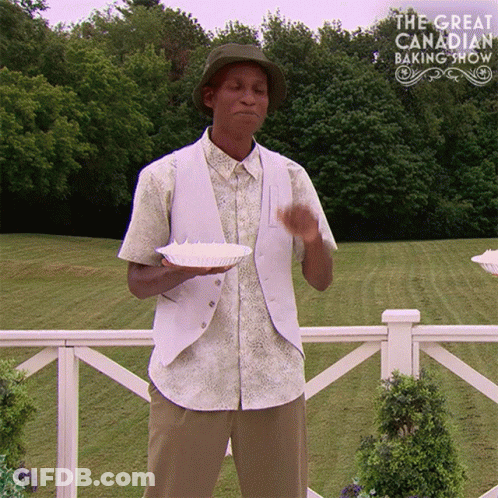 Man In Hat Holding Food In Front Of Baking Show Logo GIF